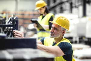 EHS man in focus in factory woman blur clipboard-300×200